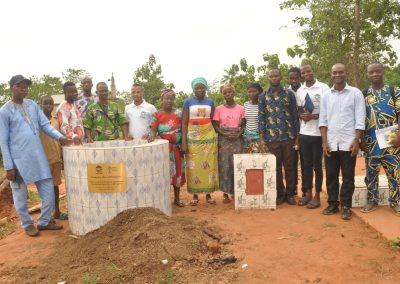 Groupe d'hommes et de femmes noirs arrêtés autour d'un biodigesteur blanc.