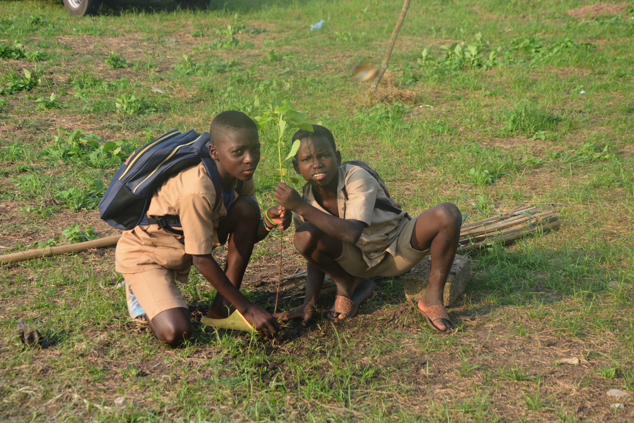 2 jeunes collégiens en kaki entrain de planter un arbre quelque part au Bénin.